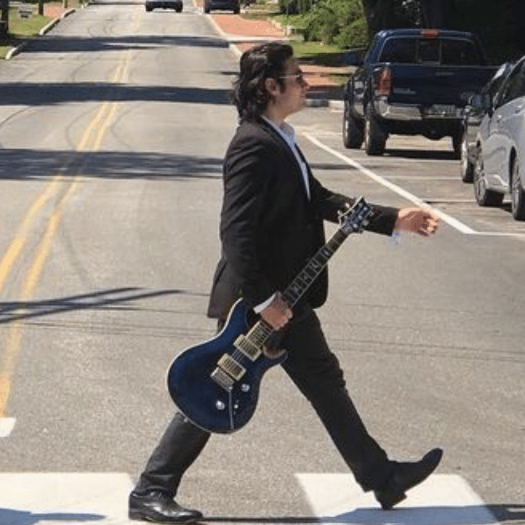 Musician Beau Dalleo walking holding guitar